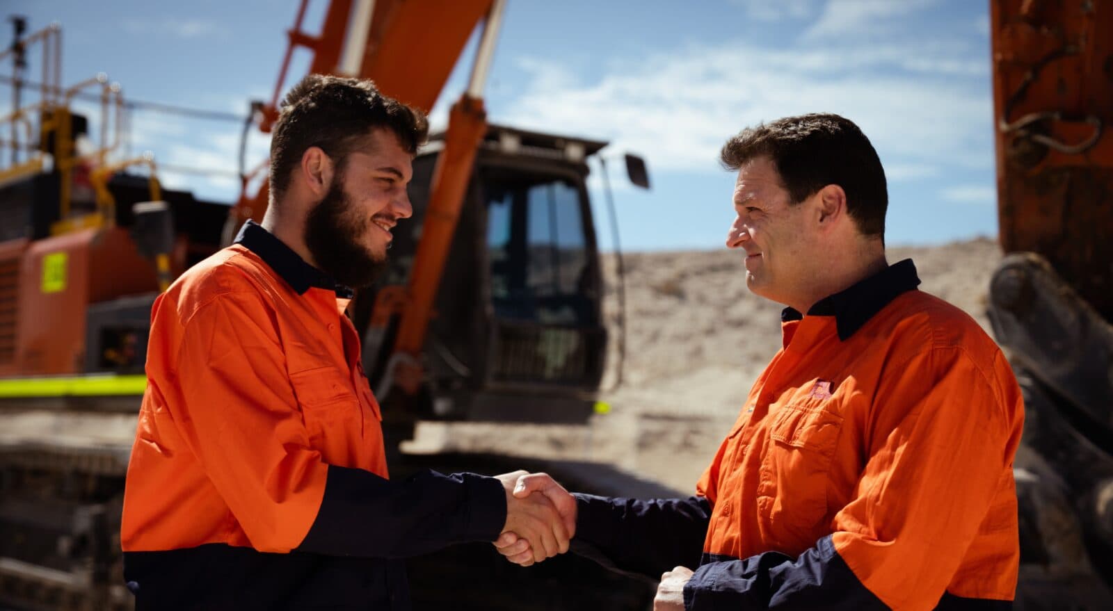 Two construction workers shaking hands on a job site