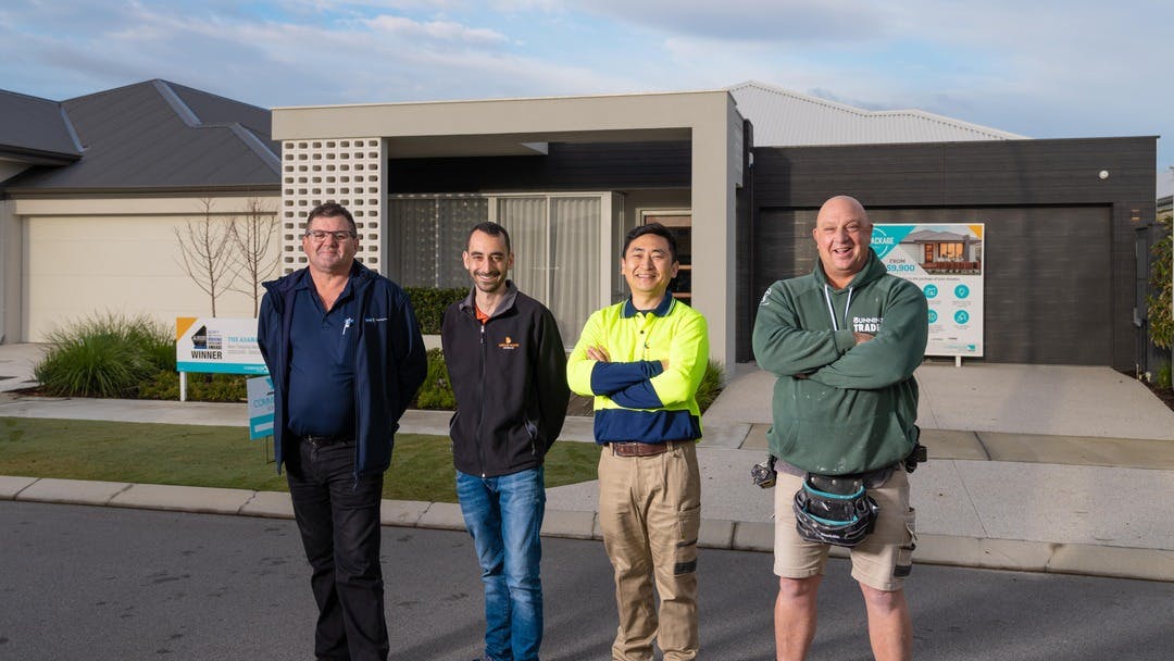 Four builder standing in front of a newly built residential house.